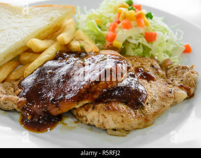 Filet de porc grillé steak avec salade et frites on white plate Banque D'Images