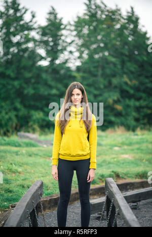 Jeune brunette woman trekking en montagne portant des sweat jaune. La tonalité de l'image. Banque D'Images