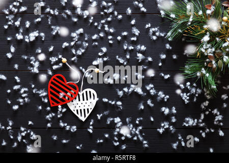 Joyeux Noël décorations, flocons, blanc rouge coeurs et arbre de Noël jouets sur noir table en bois couverte de neige, romantique maison de fond carte, Banque D'Images