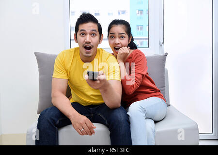 Heureux couple assis sur le canapé et regarder des films Banque D'Images