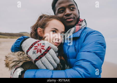 Jeune couple Hugging sur une plage d'hiver Banque D'Images