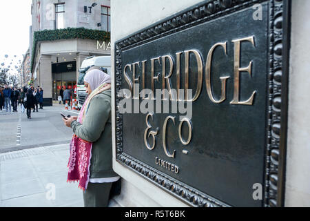 Une femme textos à l'extérieur de la célèbre Selfridges Londres magasin, sur Oxford Street, London, UK Banque D'Images