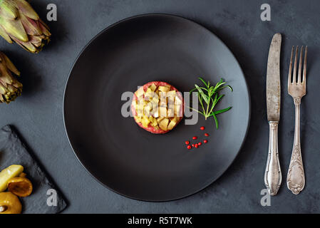 Tartare de boeuf cornichon et champignons marinés sur plaque noire. Fond sombre. Banque D'Images