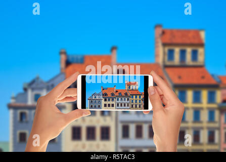 Un touriste prend une photo de belles maisons colorées sur la place du marché à Varsovie, Pologne sur un téléphone mobile Banque D'Images