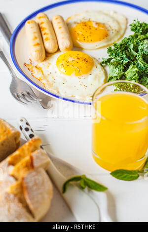 Petit-déjeuner servi avec les œufs, de la salade, des muffins et du jus d'orange sur la table en bois blanc, vue du dessus. Banque D'Images