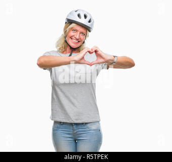 L'âge moyen caucasian woman wearing cycliste casque de sécurité au fond isolé smiling in love montrant le symbole de coeur et la forme des mains. Romantic Banque D'Images