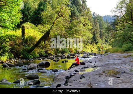 43 371,02775 Happy woman hiker assis sur la roche par Creek dans la région de Drift Creek Wilderness Area canyon, des forêts mixtes de conifères et feuillus Forêt, Oregon USA Banque D'Images