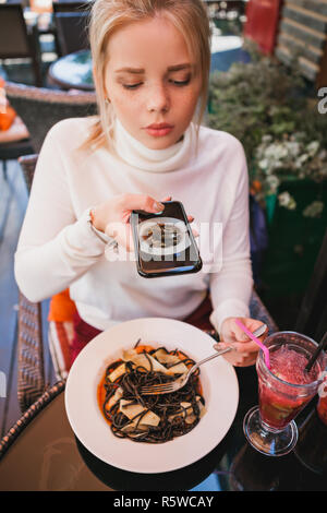 Belle jeune femme faisant photo de pâtes aux fruits de mer et noir d'encre de seiche Banque D'Images