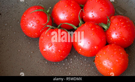 Tas de tomates juteuses mûres couvertes par les gouttes d'eau. Banque D'Images