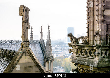 Statue en pierre de l'ange avec trompette sur le toit de la cathédrale Notre-Dame de Paris face à des chimères sur les tours gallery avec les bâtiments de la Banque D'Images