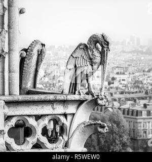 Statue de pierre d'un oiseau chimériques sur les tours galerie de la cathédrale Notre-Dame de Paris avec vue sur la ville de disparaître dans la brume au loin. Banque D'Images