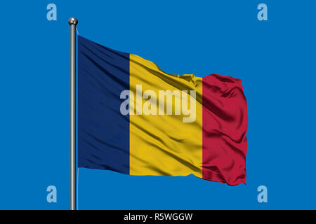 Brandissant le drapeau du Tchad dans le vent contre ciel bleu profond. Drapeau tchadien. Banque D'Images