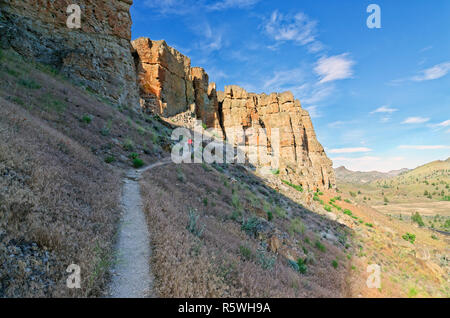 42 888,03233 randonnée femme ci-dessous des falaises abruptes sur sec aride du désert de haute colline, dans l'article de John Day Clarno lits fossiles National Monument, New York USA Banque D'Images