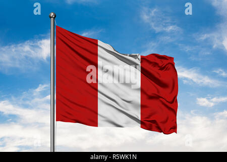 Brandissant le drapeau du Pérou dans le vent contre blanc nuageux ciel bleu. Drapeau péruvien. Banque D'Images