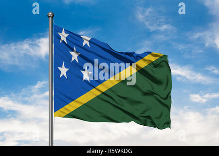 Drapeau des Îles Salomon dans le vent contre blanc nuageux ciel bleu. Banque D'Images