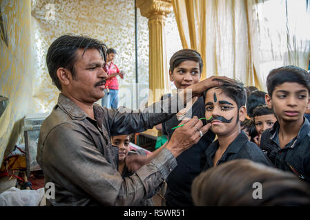 Un garçon peint des moustaches avant une performance, Pushkar, Rajasthan, Inde Banque D'Images