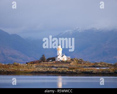 Isle Ornsay avec blanc tour de phare, île de Skye, en Écosse. Journée d'hiver ensoleillée avec les montagnes enneigées en arrière-plan. Banque D'Images