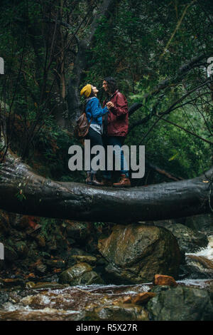 Jeune couple aimant sur un journal en face de l'autre dans la forêt à la pluie. Couple dans la pluie à la forêt. Banque D'Images