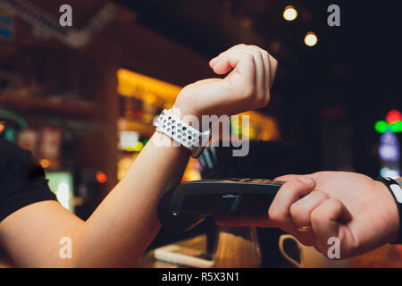 Portrait of female customer payer par le biais de smart watch at bar Banque D'Images