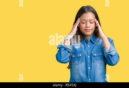 Jeune belle brunette woman wearing blue denim shirt sur fond isolé avec la main sur la tête pour la douleur dans la tête parce que le stress. Migraine souffrance Banque D'Images