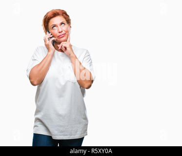 Atrractive young redhead Woman talking on smartphone sur fond isolé visage sérieux de penser à question, idée très confus Banque D'Images