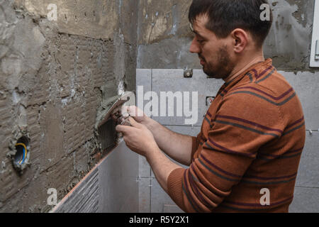 Constructeur professionnel Application de colle avant la pose de carreaux de céramique sur le mur Banque D'Images