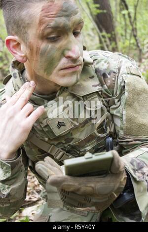 Le Sgt. Jackson Wilson, un résident de Houston, Texas et un membre de la 45ème Infantry Brigade Combat Team participant à la 7e Armée Traning sous-commande Officer Academy Cours de chef de base lors d'un déploiement à l'Ukraine, s'applique au cours d'un camouflage de la formation de la situation de l'exercice au centre d'instruction au combat de Yavoriv sur le maintien de la paix et la sécurité internationale, près de l'viv, Ukraine, le 20 avril. Banque D'Images