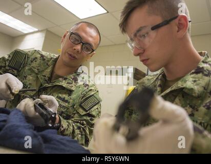 MANAMA, Bahreïn (24 avril 2017) Gunner's Mate 2e classe Raymond Villegas (à gauche) aide Gunner's Mate Seaman Braden Maynard (droite), tous deux assignés à munitions du détachement de la marine commande Bahreïn, nettoyer M9 Beretta 9mm pistolets après avoir terminé un cours de qualification d'armes légères et de petit calibre à l'éventail sur la base navale américaine (NSA) BAHREÏN 24 Avril. Banque D'Images