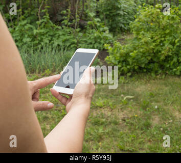 Femme blonde utilise un smartphone pour prendre un en selfies le parc à l'été Banque D'Images