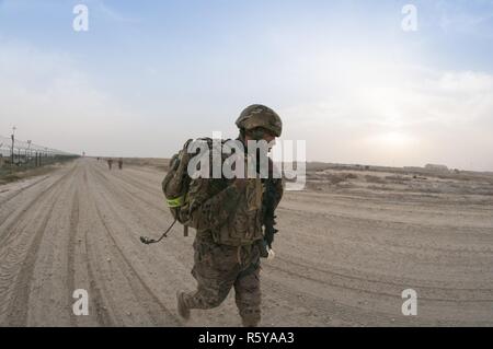 Le Sgt. Calvin Grimes, un soldat avec le 595th bataillon de transport, pousse vers la ligne d'arrivée de la 1ère Commande de soutien (Théâtre) Meilleur guerrier concurrence 10-mile ruck mars au Camp Arifjan, au Koweït le 16 avril, 2017. Banque D'Images