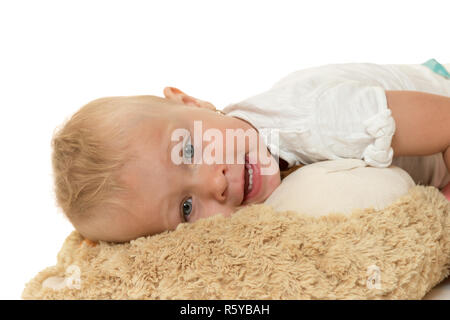 Souriant bébé fille est couchée sur une peluche Banque D'Images