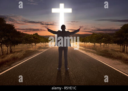 Portrait of man raising hand en priant à Dieu avec croix lumineuse Banque D'Images