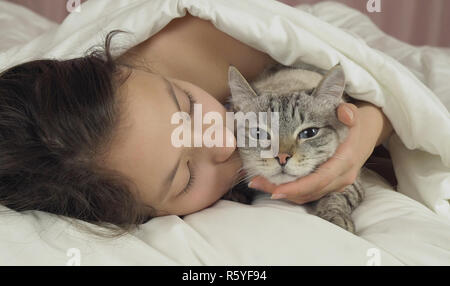 Happy teen girl baisers et des pourparlers avec Thai cat in bed Banque D'Images