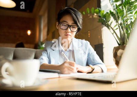 Dans les verres pensive businesswoman making notes Banque D'Images