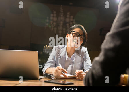 Madame asiatique travaillant avec son collègue de bureau sombre Banque D'Images