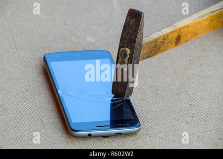Marteau et d'un smartphone. L'écran du smartphone, une fracture de ha Banque D'Images
