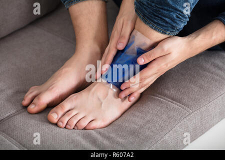 Person's Hand Holding Ice Pack Gel Sur la cheville Banque D'Images