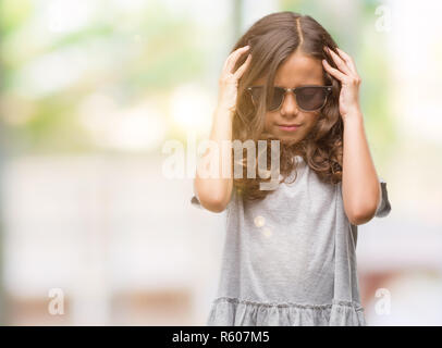 Brunette woman wearing sunglasses avec la main sur la tête pour la douleur dans la tête parce que le stress. Souffrant de migraines. Banque D'Images