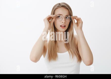 Fille voit mieux que d'essayer de nouvelles lunettes prescrites commandé en boutique. Portrait de charme calme et féminine intrigué jeune femme aux cheveux blonds puttin Banque D'Images