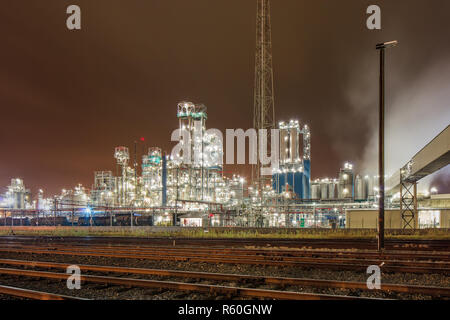 Scène de nuit à l'usine de production pétrochimique illuminé avec les voies ferrées à l'avant, Anvers, Belgique. Banque D'Images