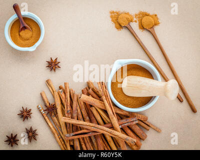 Composition de bâton de cannelle et la cannelle en poudre dans un mortier blanc à la badiane, les feuilles de laurier et cuillère en bois sur fond brun . Banque D'Images