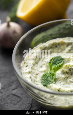 Dans le Tzatziki bol en verre sur la pierre noire table verticale Banque D'Images