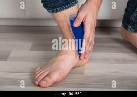 Person's Hand Holding Ice Pack Gel Sur la cheville Banque D'Images