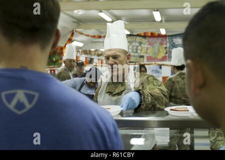 U.S. Air Force Brig. Darren Cole, directeur général, le Commandement central américain, Centre des opérations de distribution de déploiement sert un repas de Thanksgiving de soldats au Camp Arifjan, au Koweït, du 22 novembre 2018. Avoir un repas de Thanksgiving traditionnel lors d'un déploiement outre-mer avec leur famille de l'armée américaine améliore le moral des soldats quand ils sont loin de chez eux. Banque D'Images