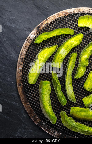 Fruits confits de pomelo dans un bol de cuivre sur une pierre grise Banque D'Images