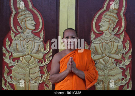 Un moine bouddhiste à Wat Mongkon (Mongkol) Nimit dans la ville de Phuket, Phuket, Thaïlande, saluant le visiteur avec un Wai, le salut traditionnel thaïlandais Banque D'Images