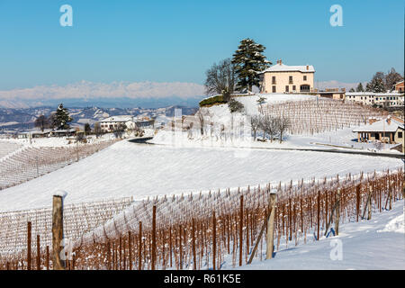 Avis de maisons rurales et de vignes sur les collines enneigées sous ciel bleu en Piémont, Italie du Nord. Banque D'Images