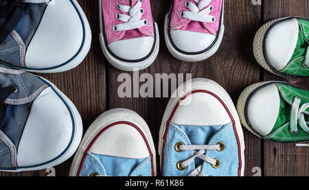 Quatre paires de vieilles chaussures textile sur un fond noir, femmes, les hommes et les chaussures pour enfants Banque D'Images