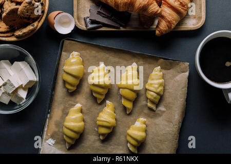 Vue du dessus du bac avec la pâte pour croissants, ingrédients et tasse de café sur la table Banque D'Images