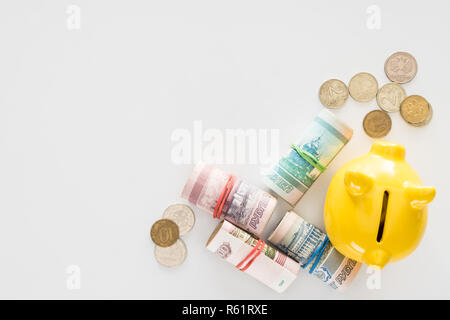 Portrait de jaune tirelire et divers billets russe laminés avec pièces de monnaie sur la surface blanche Banque D'Images